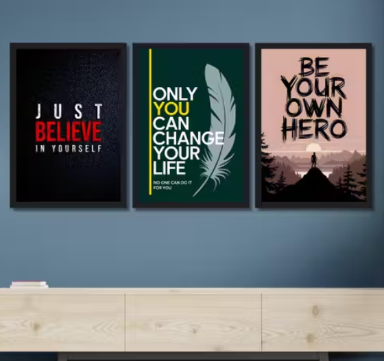 Three motivational posters on a wall with a wooden shelf below.